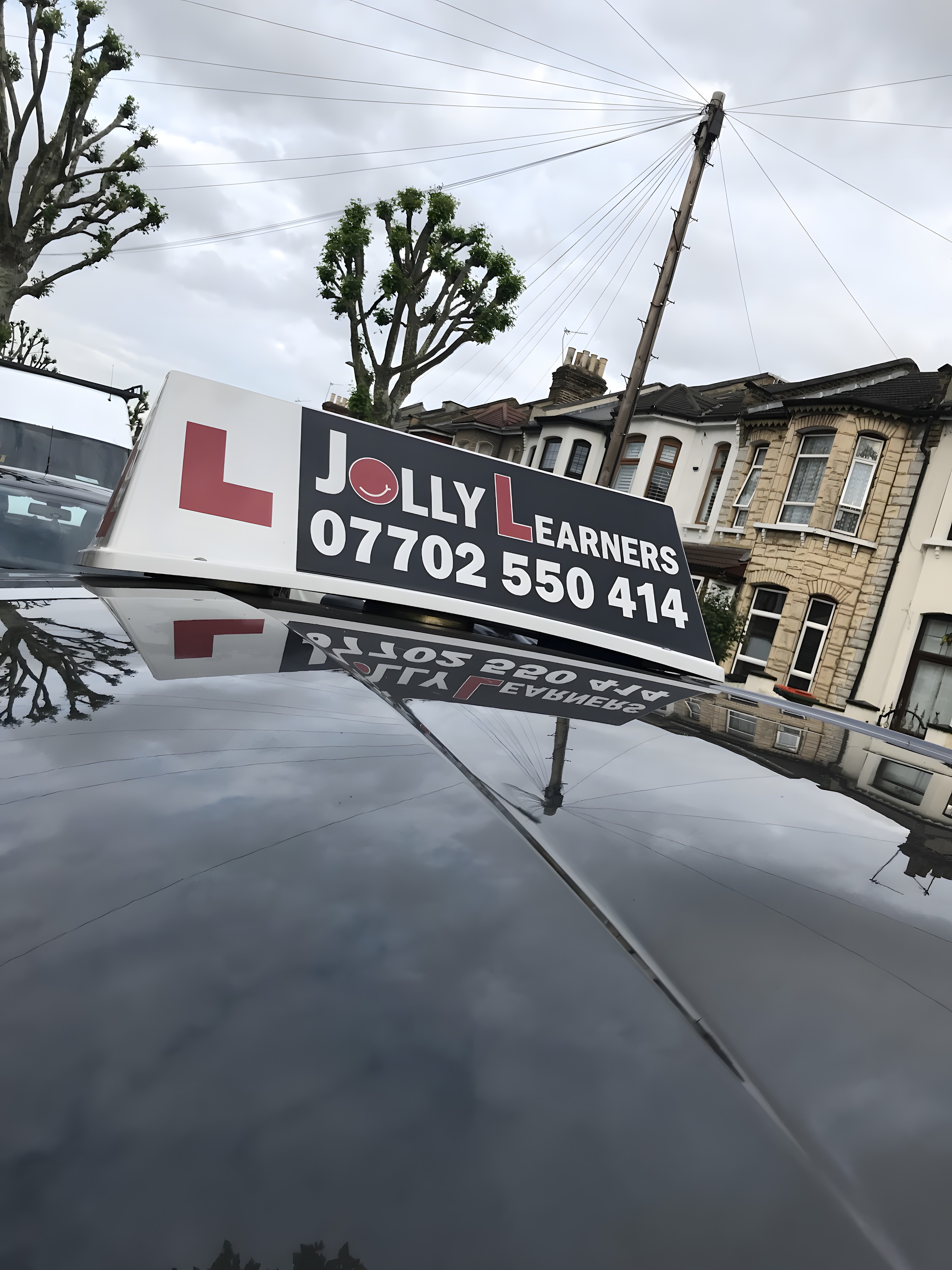 Jolly Learners roof sign showing the phone number 07702 550414 on a tuition car in East Ham